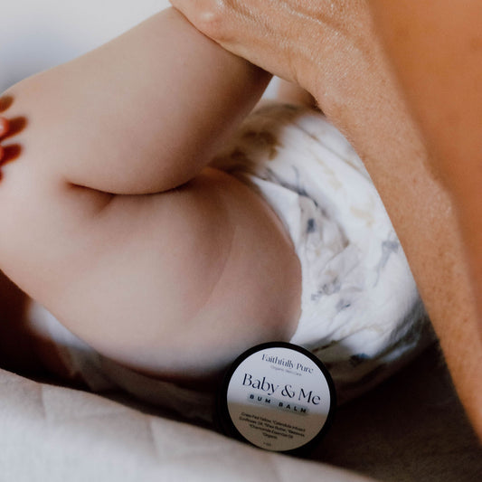 Baby bottle labeled 'Baby & Me' held by a hand with a ring, on a neutral background
