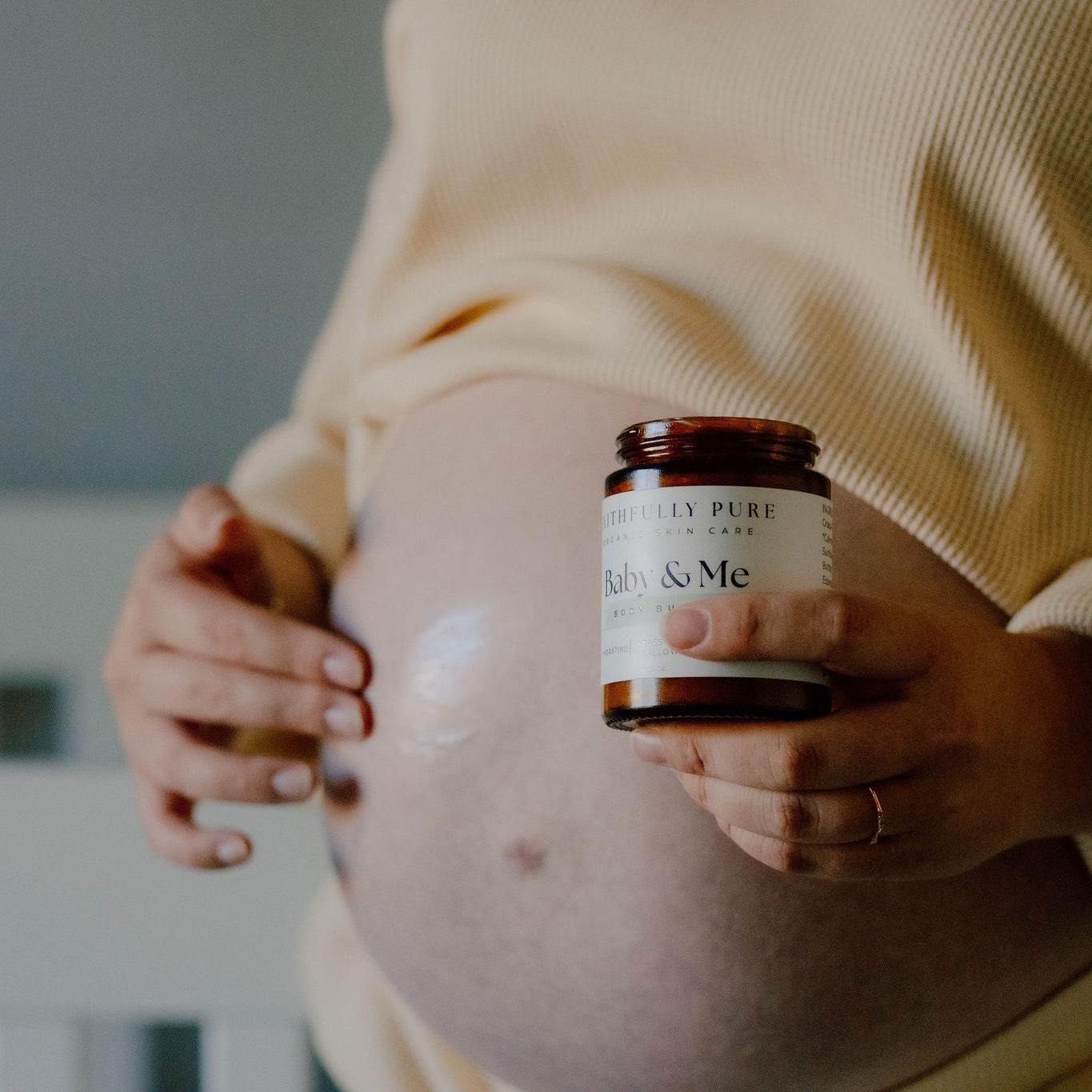 Pregnant person holding a jar labeled 'Baby & Me' against their belly.